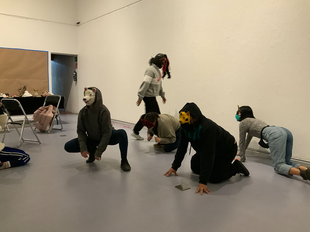 photo of five performers with animal masks crawling, crouching, walking in a galery space